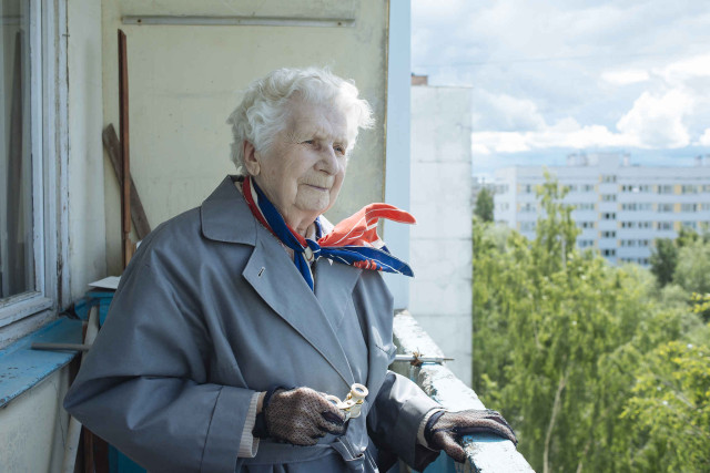 Антонова Александра Николаевна стоит на балконе, чтобы посмотреть на окрестности в бинокль.